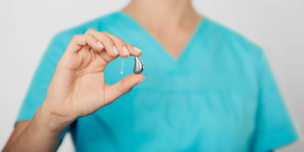 Close-up of a hearing specialist holding a mRIC R hearing aid.